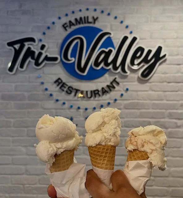 The Tri-Valley sign on the white brick wall, with three ice cream cones held up in front of it