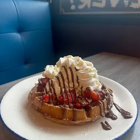 A waffle with whipped cream in a blue booth