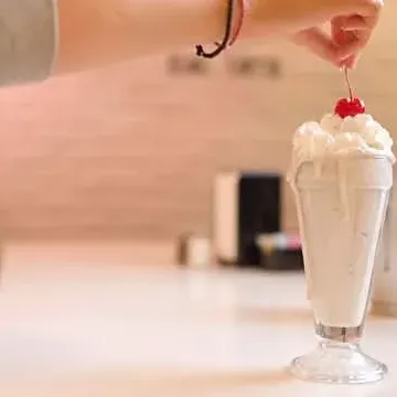 A milkshake at the counter, cherry on top